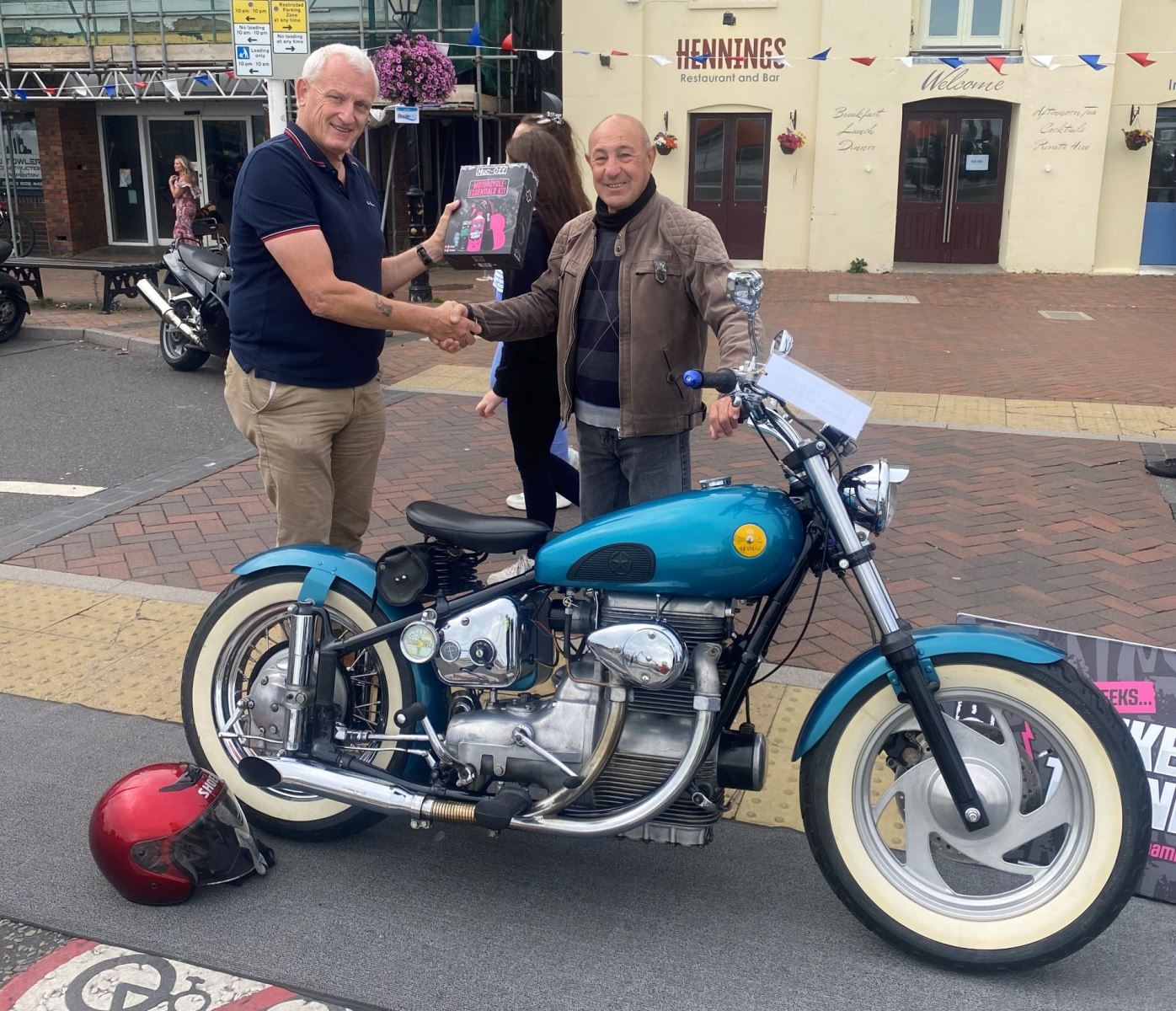 Man shaking the hand of another man inforont of a bike 